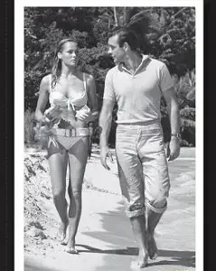 Black-and-white photo of a man and woman walking outdoors in casual summer attire.