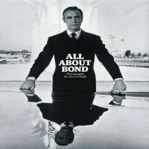 A man in a suit stands by a reflective surface with the text 'ALL ABOUT BOND'.